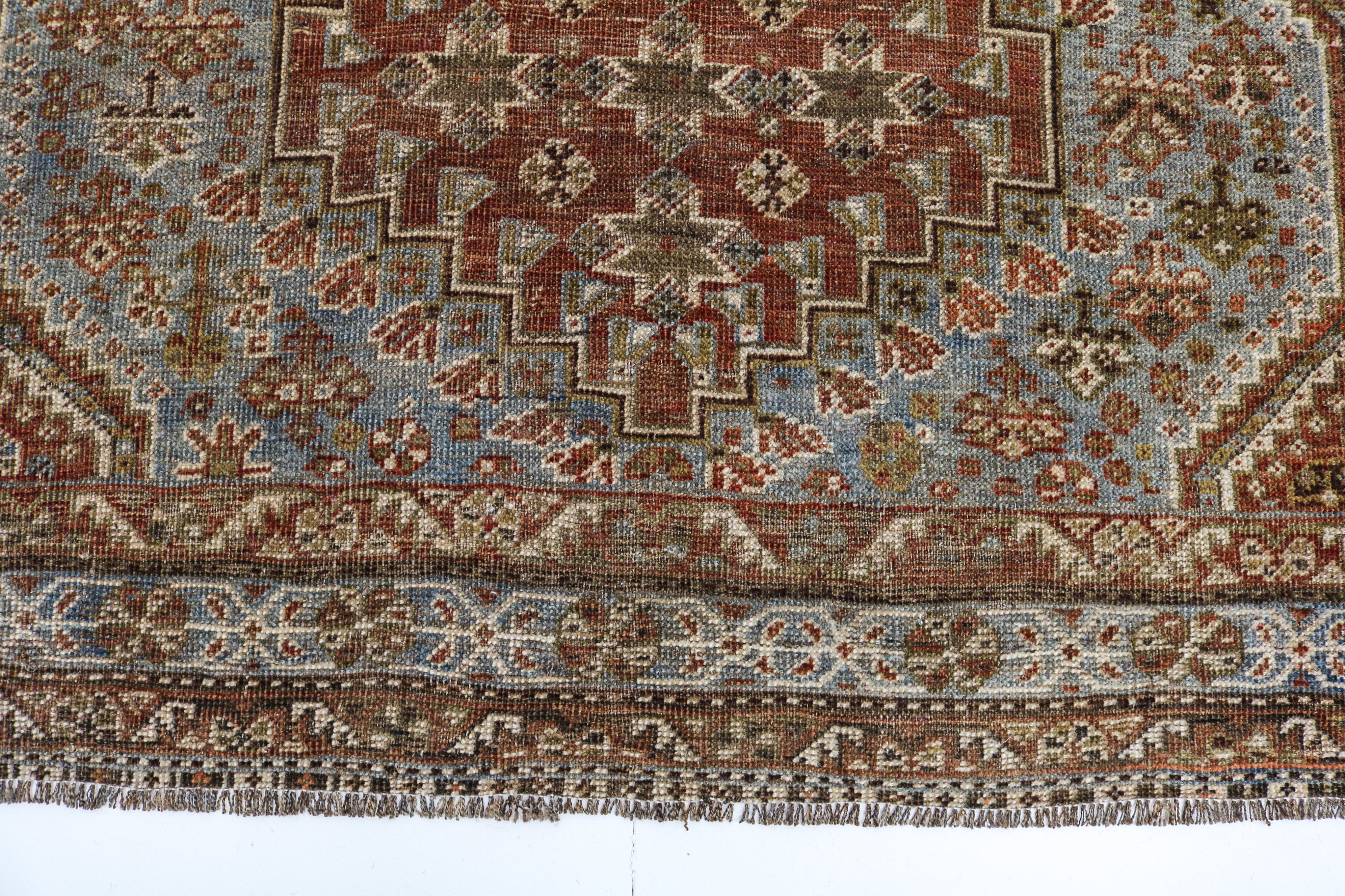 Antique Qashqai rug detail featuring traditional stepped medallion and faded blue accents