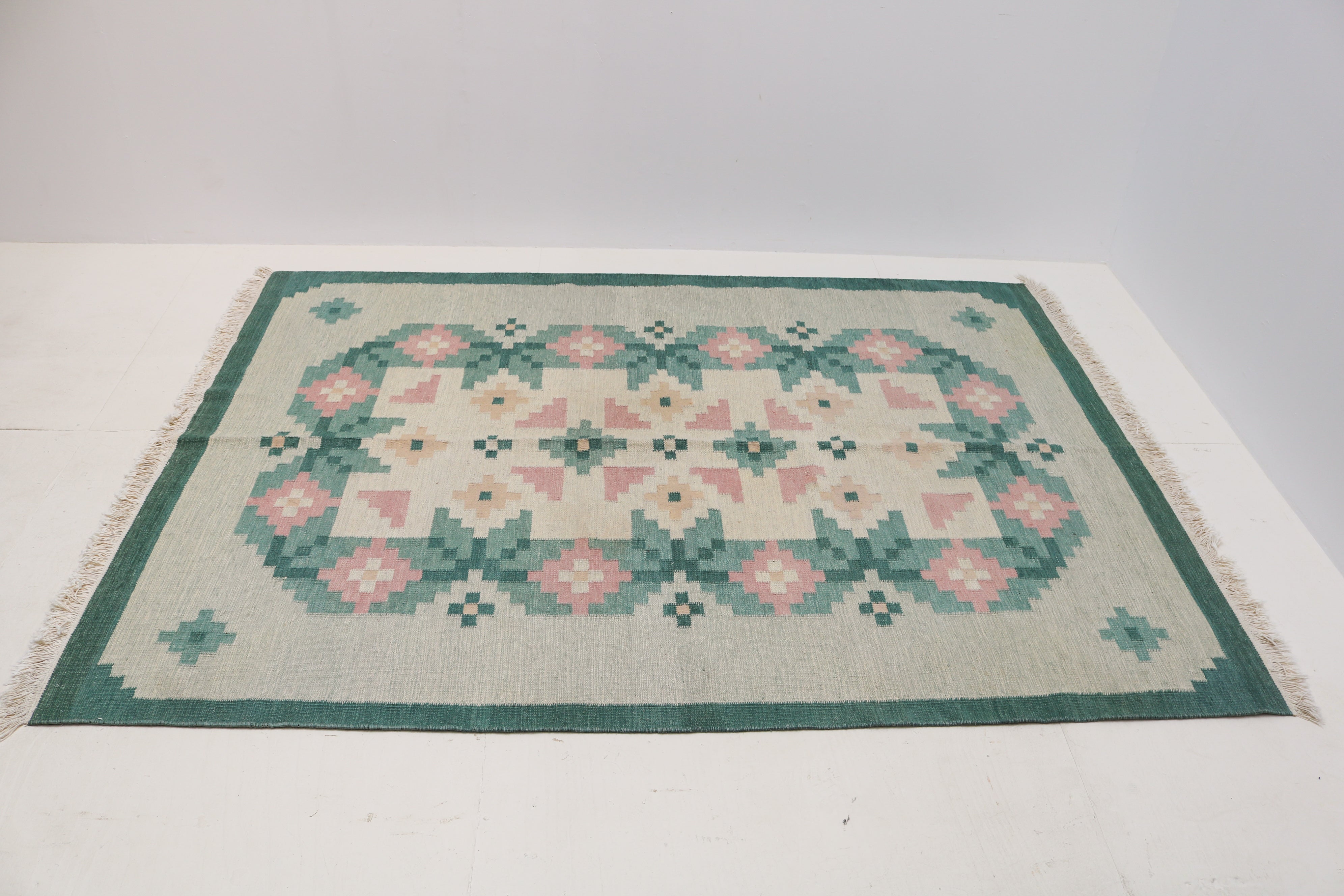Large mid-century Swedish kilim rug with green border and stylised floral design