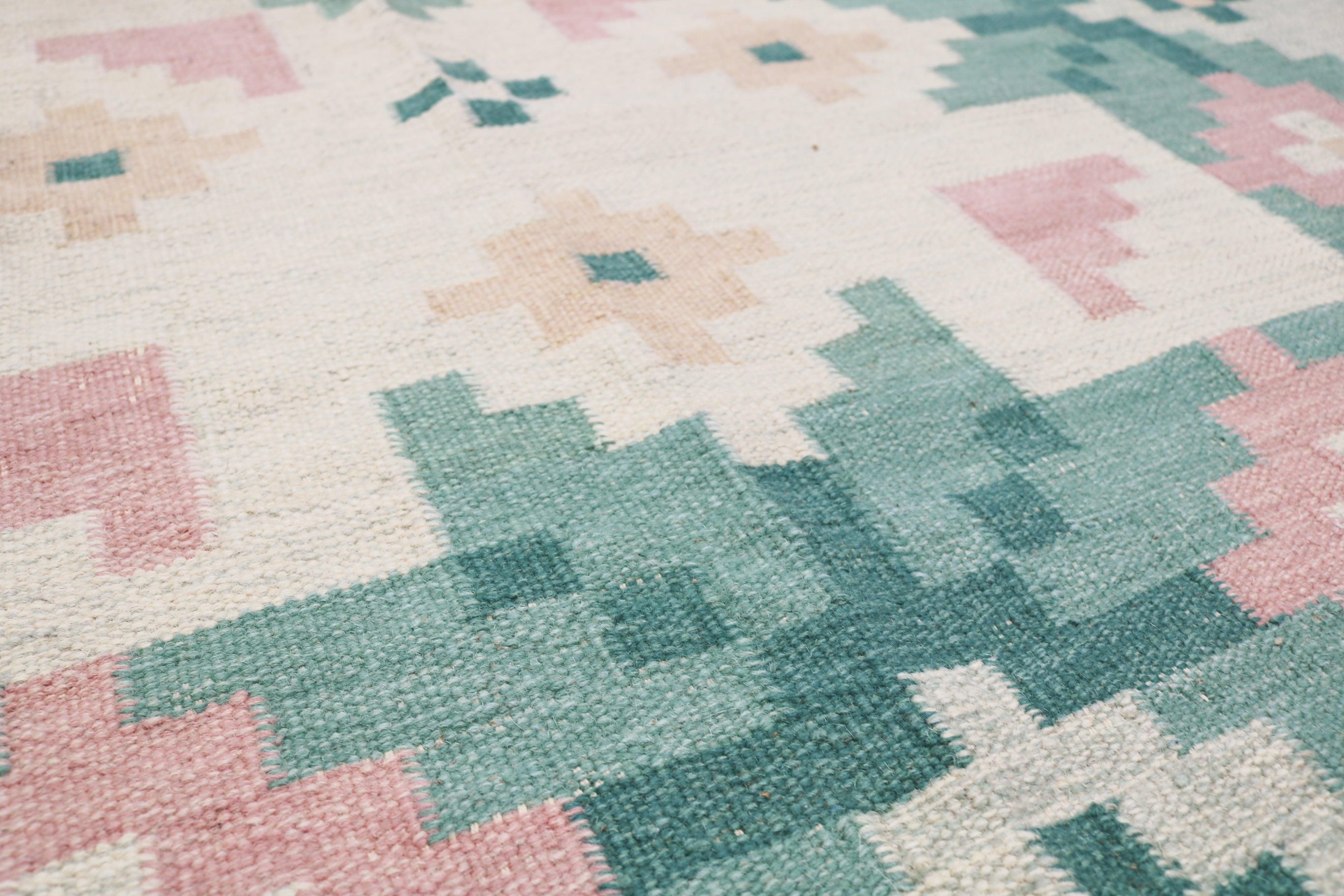Close-up of vintage Swedish kilim showing green border, pink flower and handwoven wool texture 7