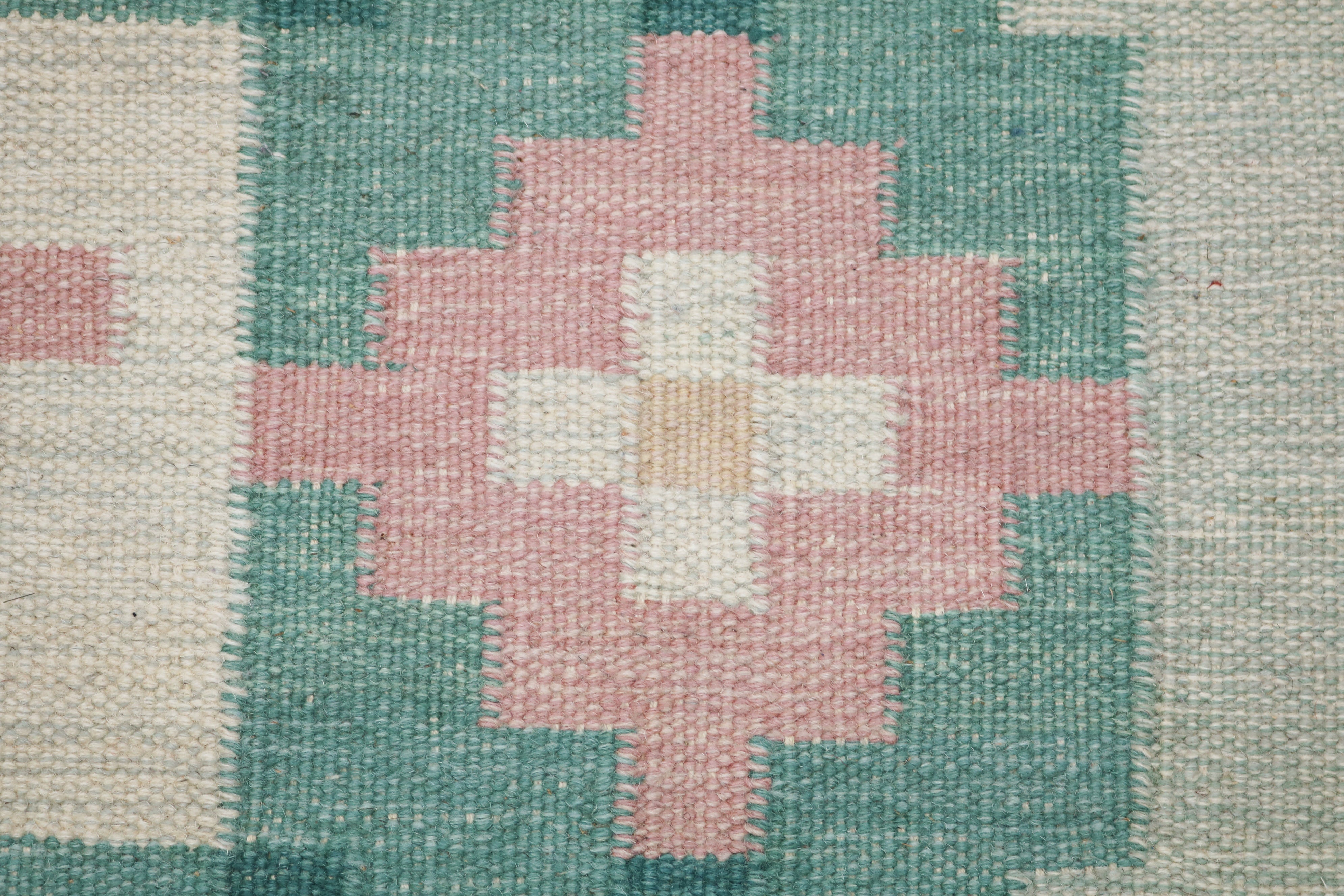 Close-up of vintage Swedish kilim showing green border, pink flower and handwoven wool texture 10