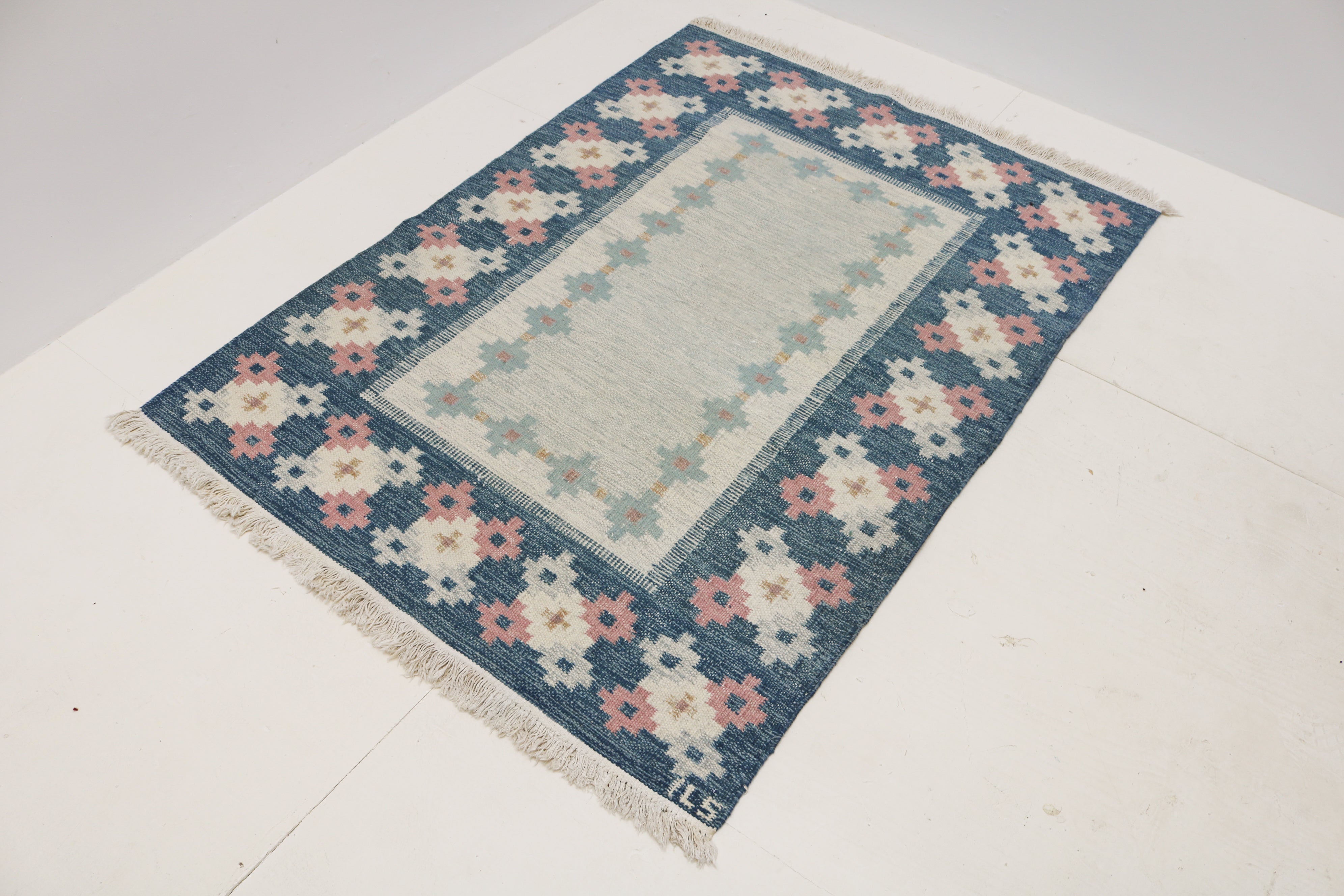 Close-up of handwoven vintage Swedish kilim with blue, ivory and pink geometric flowers