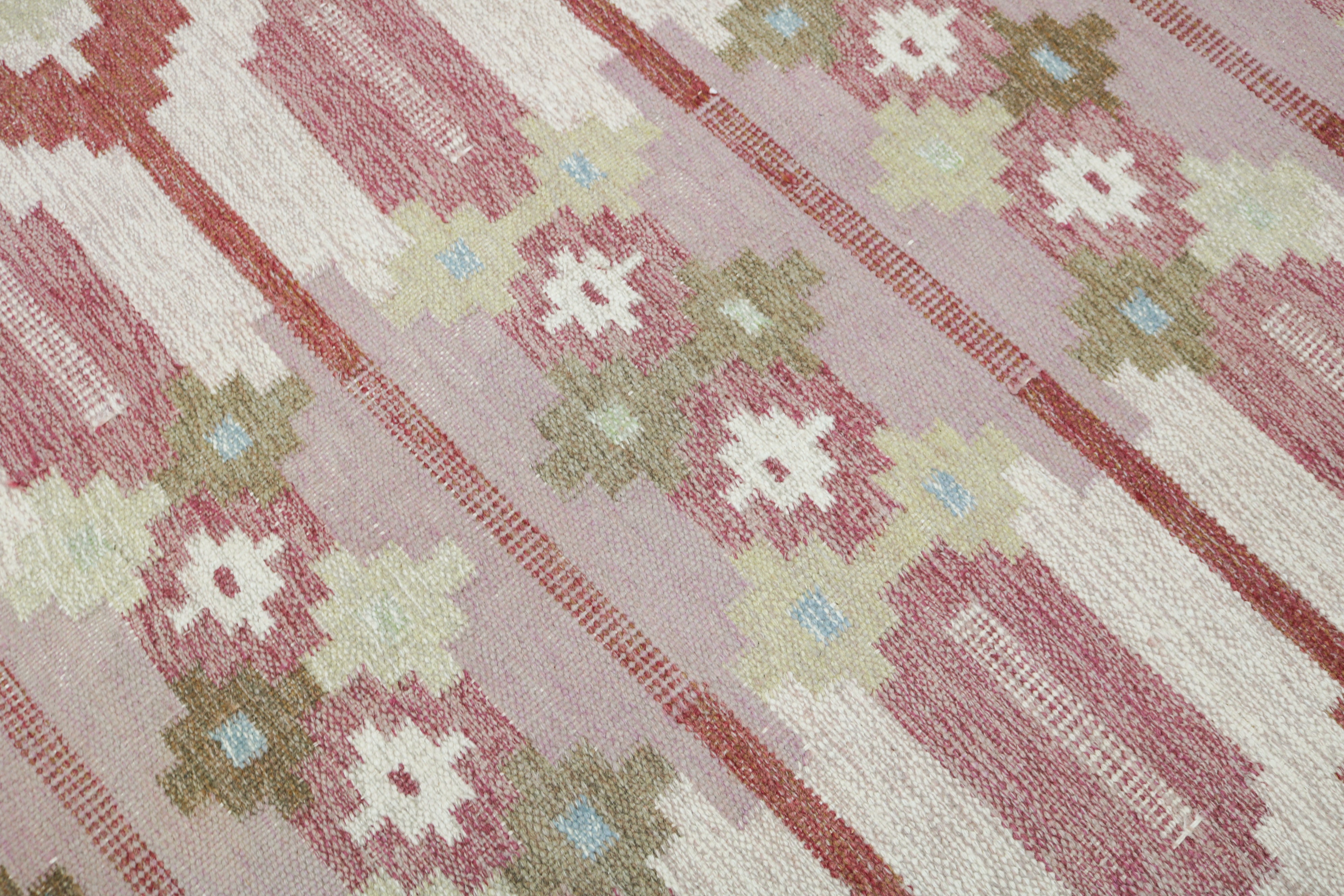Geometric border detail of vintage Swedish kilim rug in dusty rose, ivory and warm brown