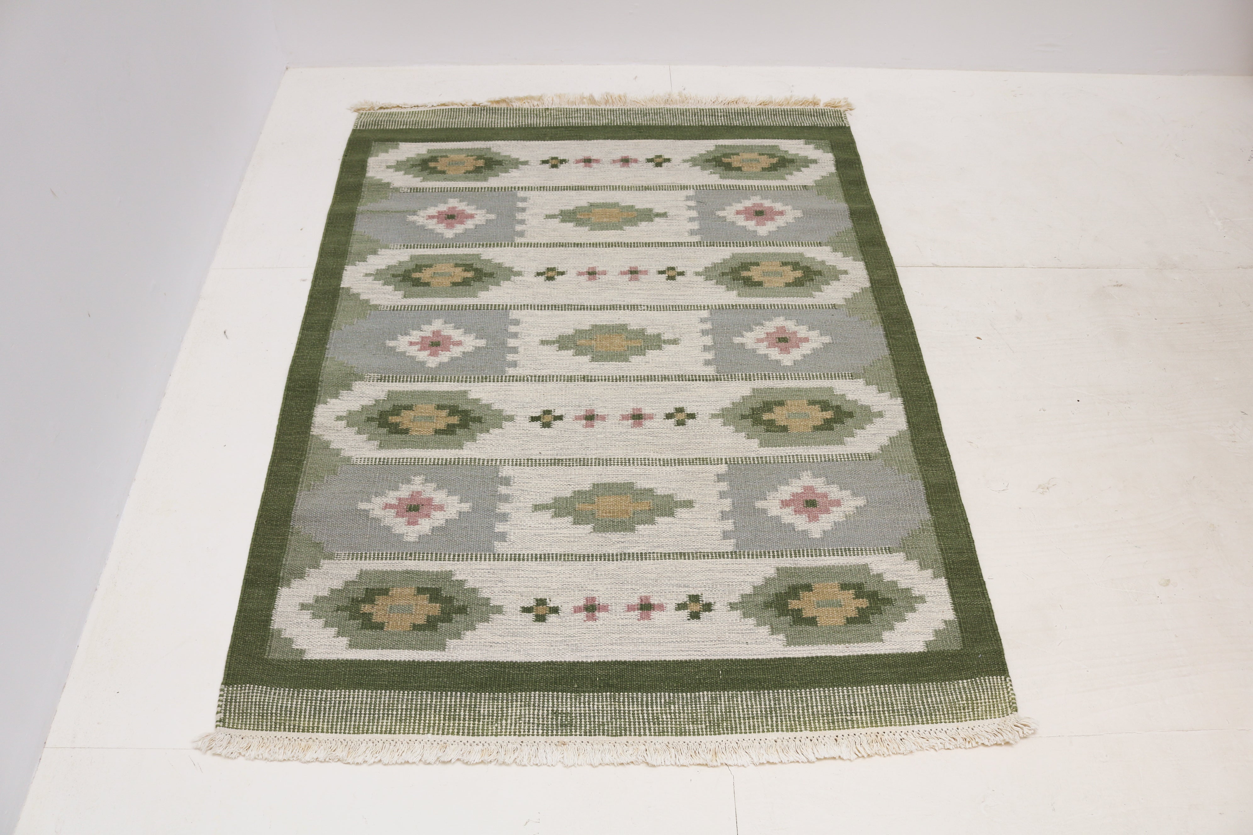 Detail of vintage Swedish Kilim rug with soft green grey ivory and dusty pink geometric design