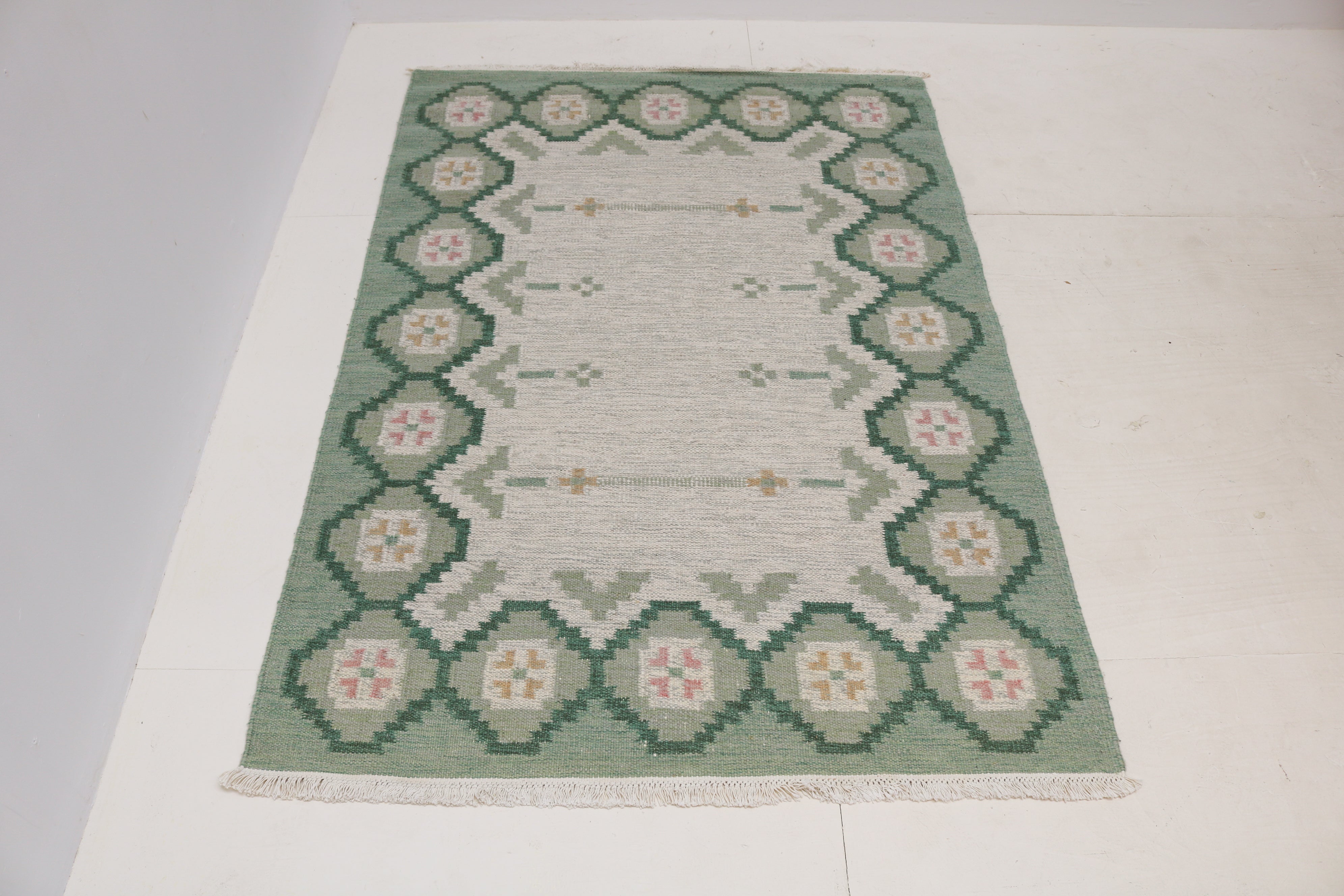 Detail of vintage Swedish Kilim rug with soft green grey ivory and dusty pink geometric design