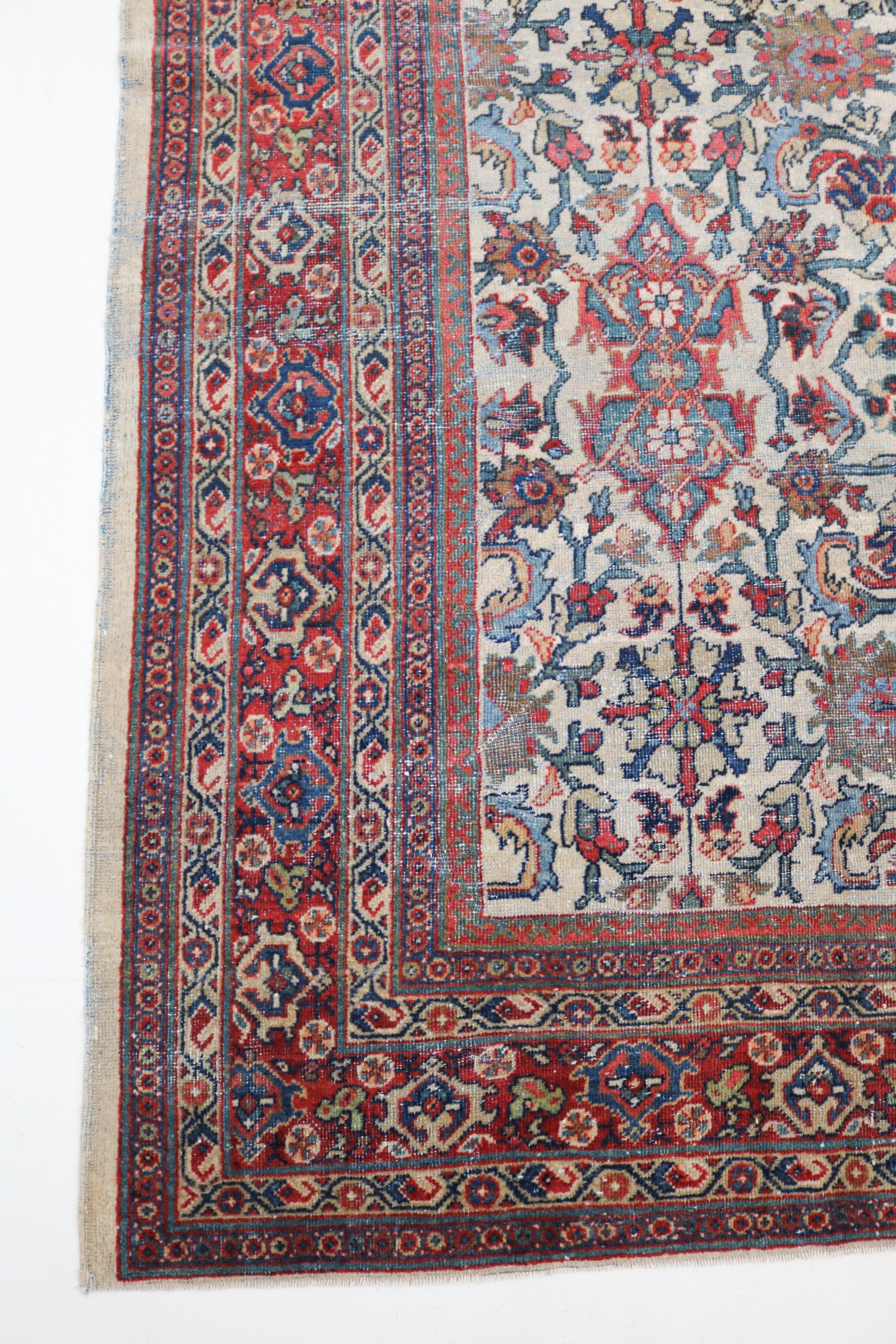 Close-up of antique Persian Mahal rug showing hand-knotted floral motifs, ivory field and terracotta red border
