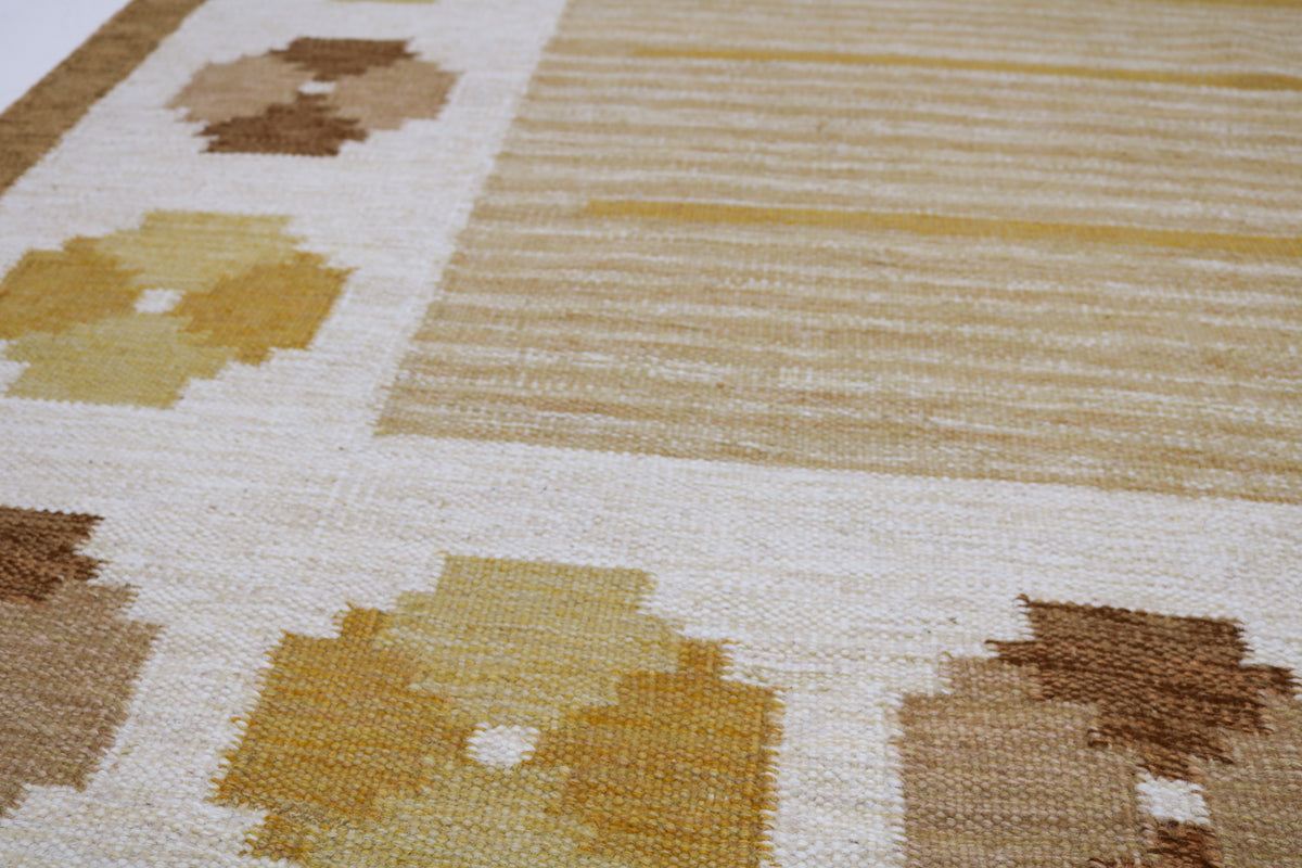 Close-up of Kilim rug with geometric floral motifs in mustard yellow, tan and warm brown