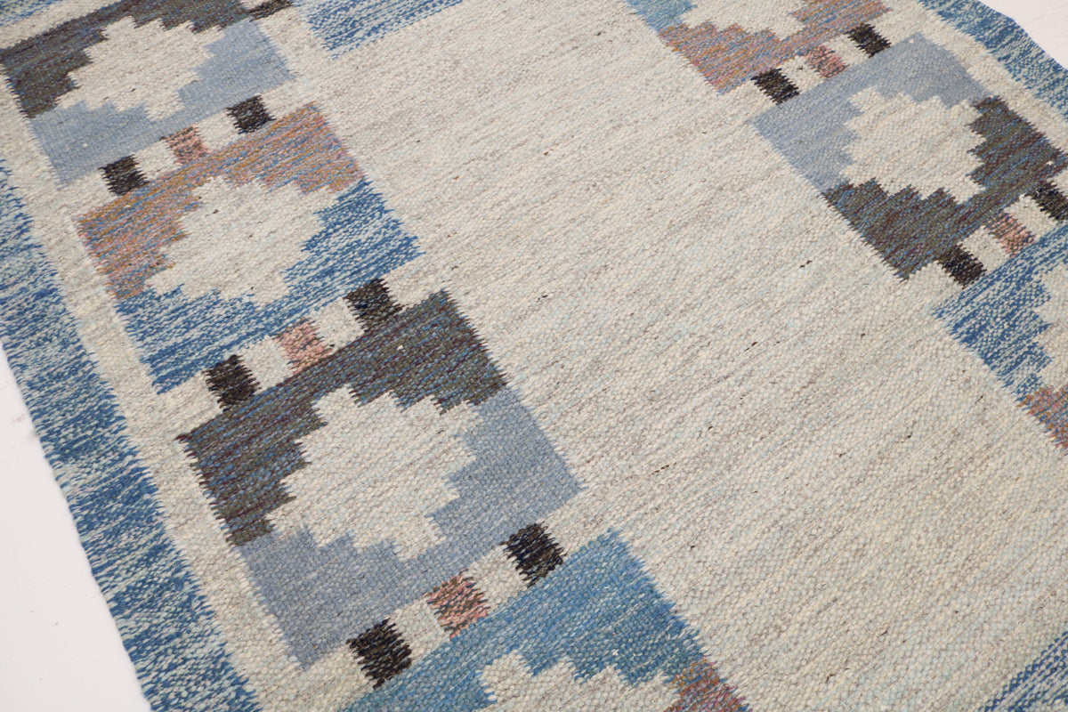 Close-up of Kilim rug with blue-grey geometric medallions and subtle dusty pink accents