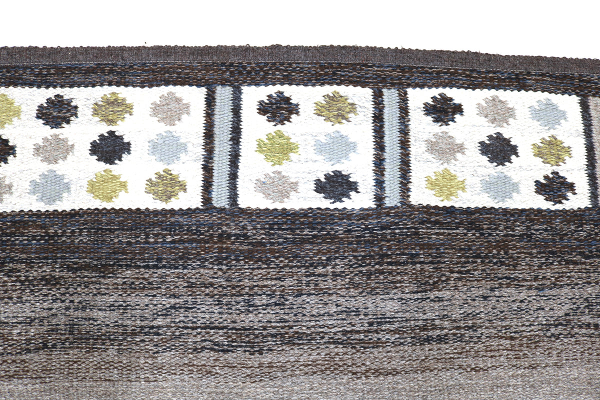 Close-up of Kilim border with repeating floral motifs in black, cream and green