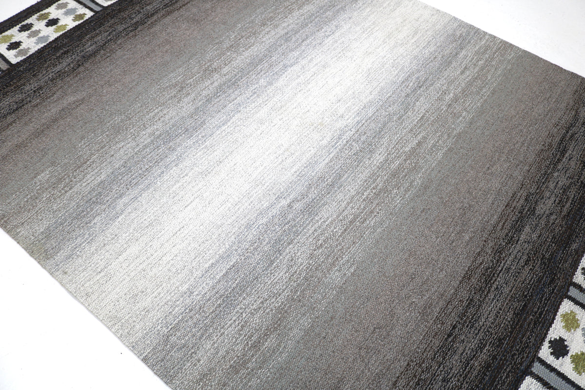 Angled view highlighting the tonal grey field and patterned decorative border