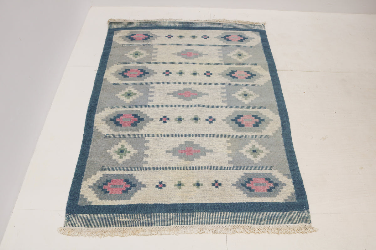 Full view of vintage Swedish Kilim rug with alternating geometric bands and floral motifs