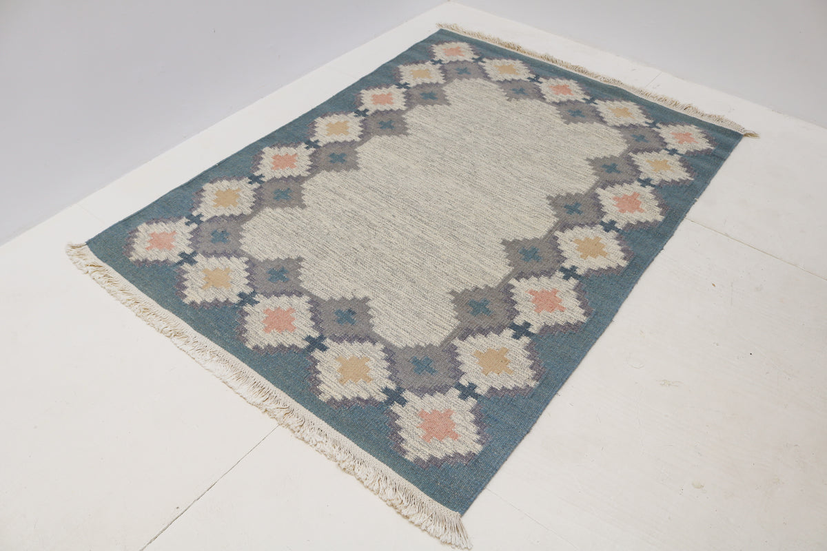 Vintage Swedish Kilim rug showcasing a simple ivory centre with patterned geometric border
