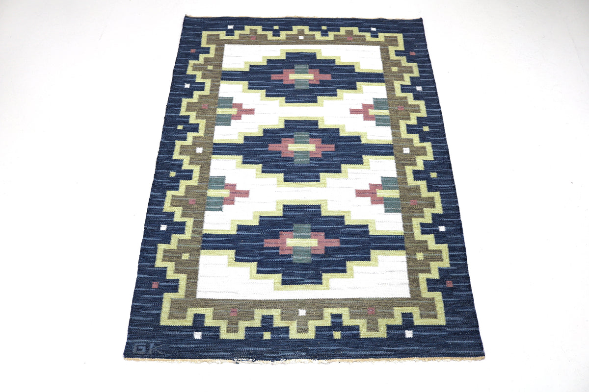 Full view of vintage Swedish Kilim rug with repeating geometric patterns and dark navy border
