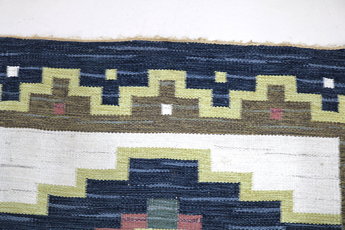 Detailed view of Swedish Kilim rug with repeating geometric patterns in navy, ivory and olive
