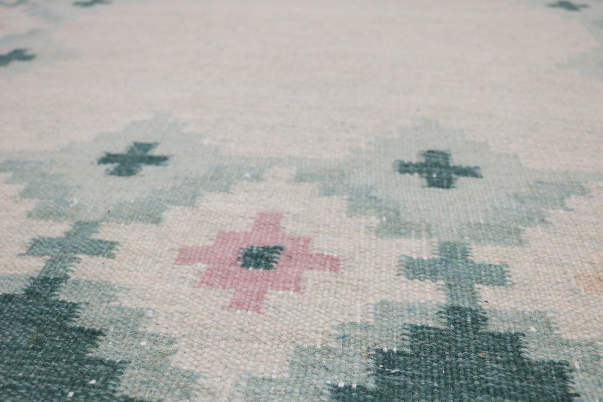Detailed Kilim rug field featuring stylised pink and beige floral motifs on ivory
