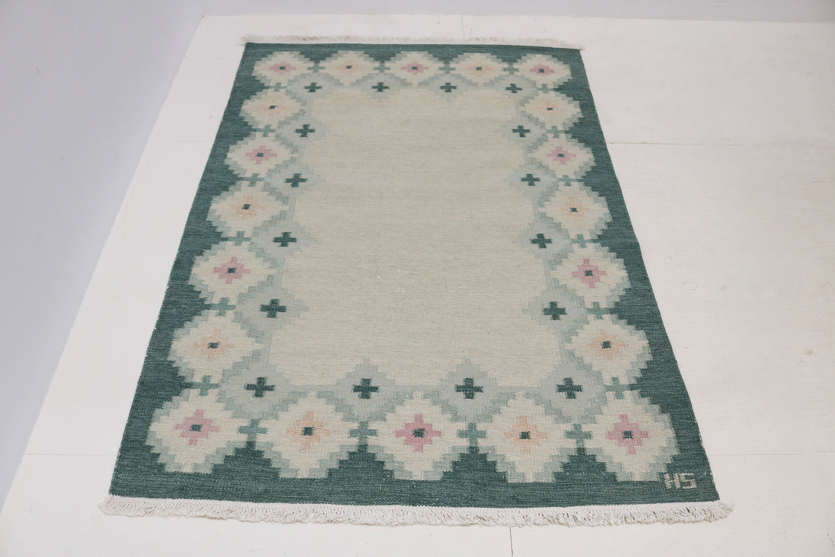 Full view of vintage Swedish Kilim rug with spacious ivory field and decorative border

