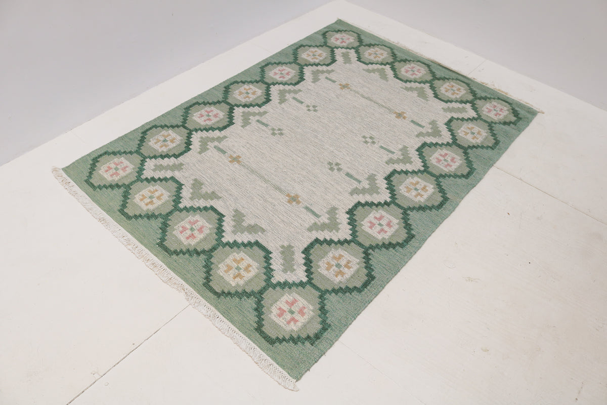 Vintage Swedish Kilim rug showcasing a spacious pale grey centre and decorative green border