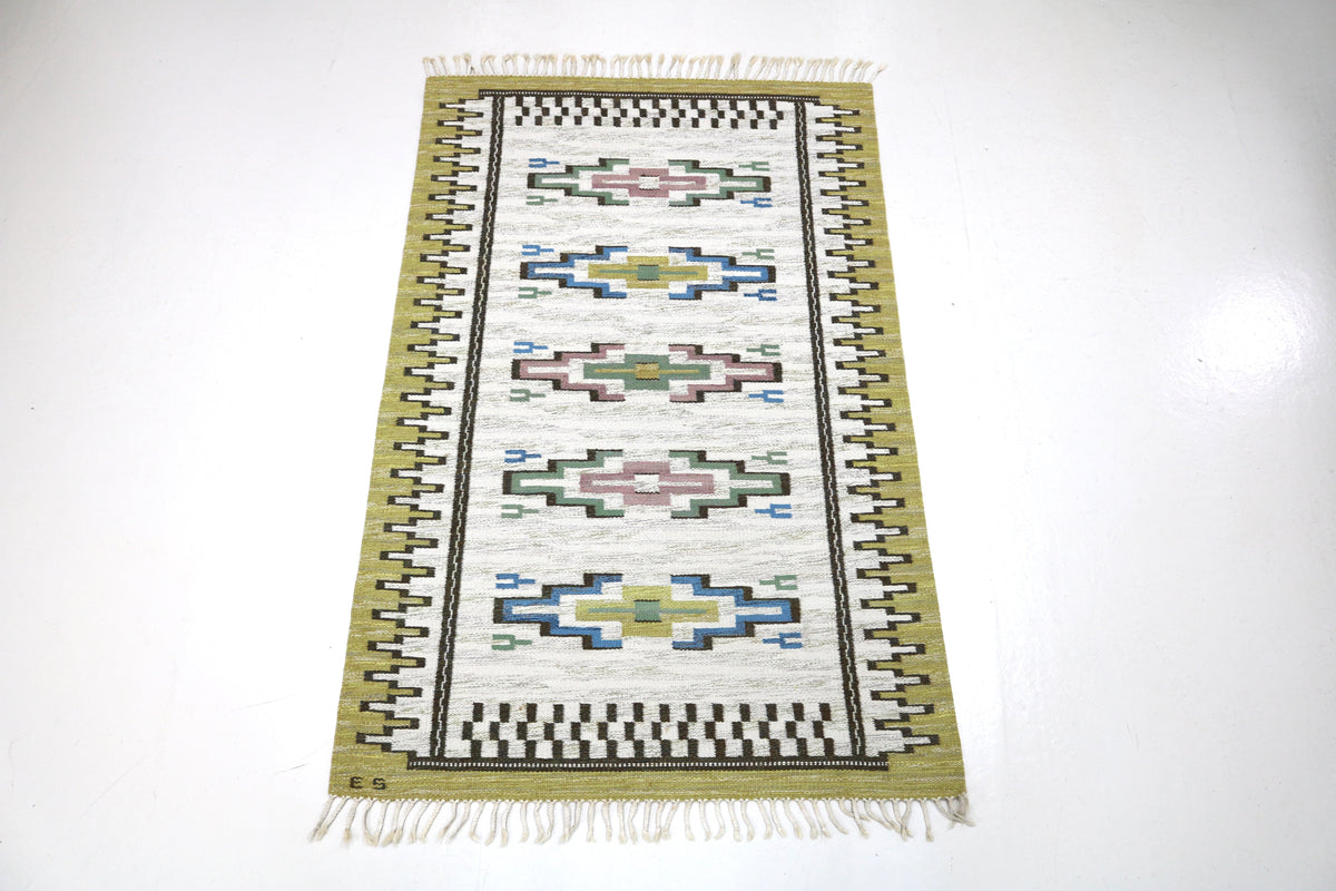 Full view of vintage Swedish Kilim rug with repeating geometric patterns and fringed ends