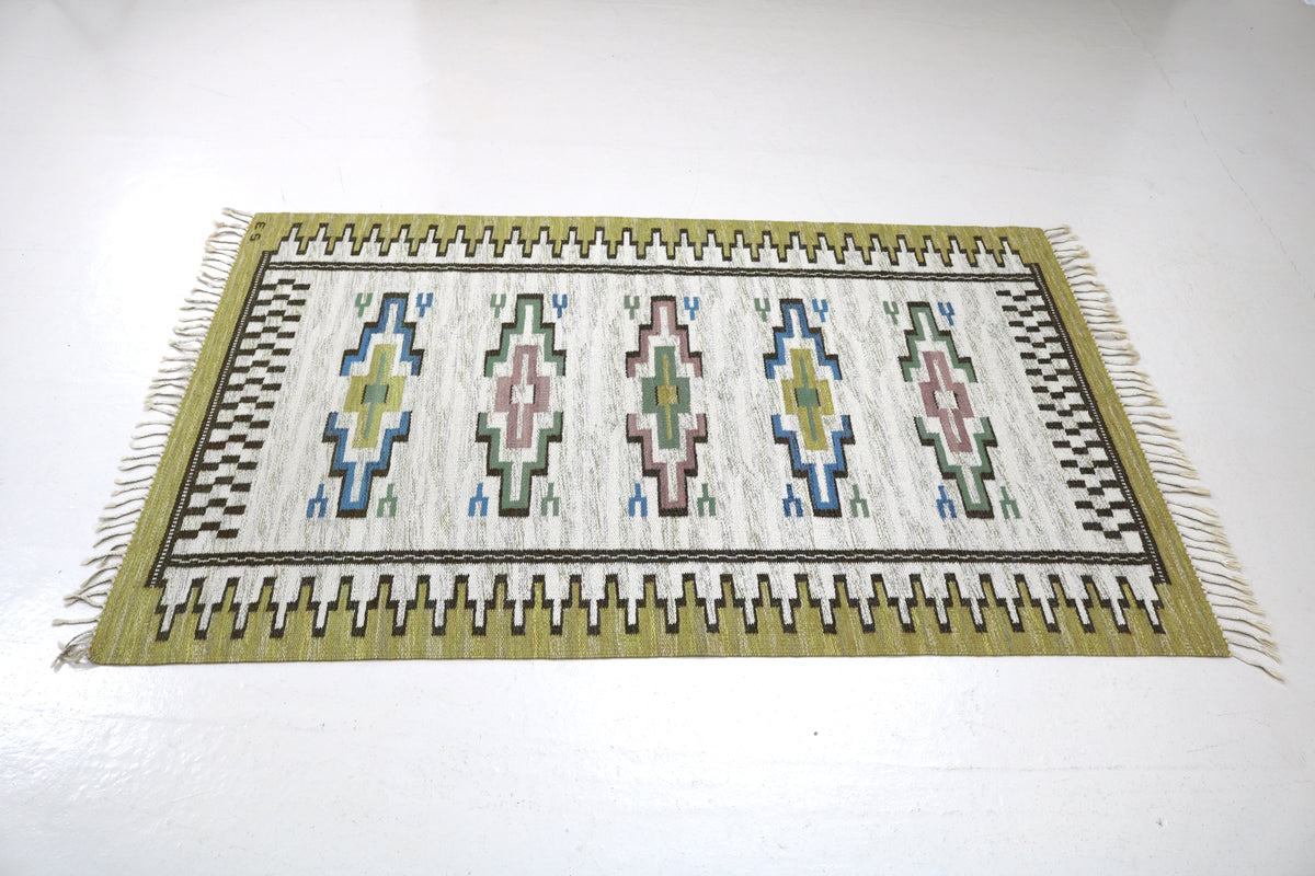 Vintage Swedish Kilim rug showcasing symmetrical geometric patterns and contrasting olive border