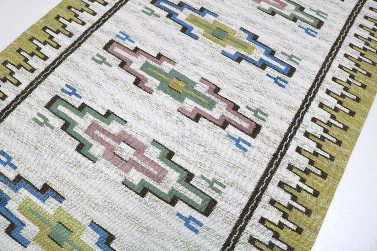 Close-up of Kilim rug with blue, green, pink and ochre geometric motifs