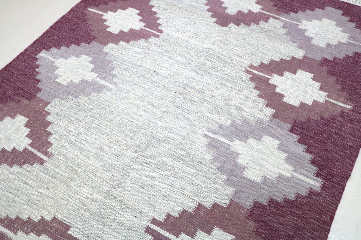 Close-up of vintage Swedish Kilim rug featuring repeating diamond motifs in burgundy and ivory