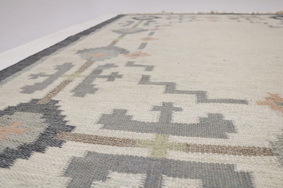 close-up of Kilim rug field featuring stylised geometric motifs in muted grey and taupe