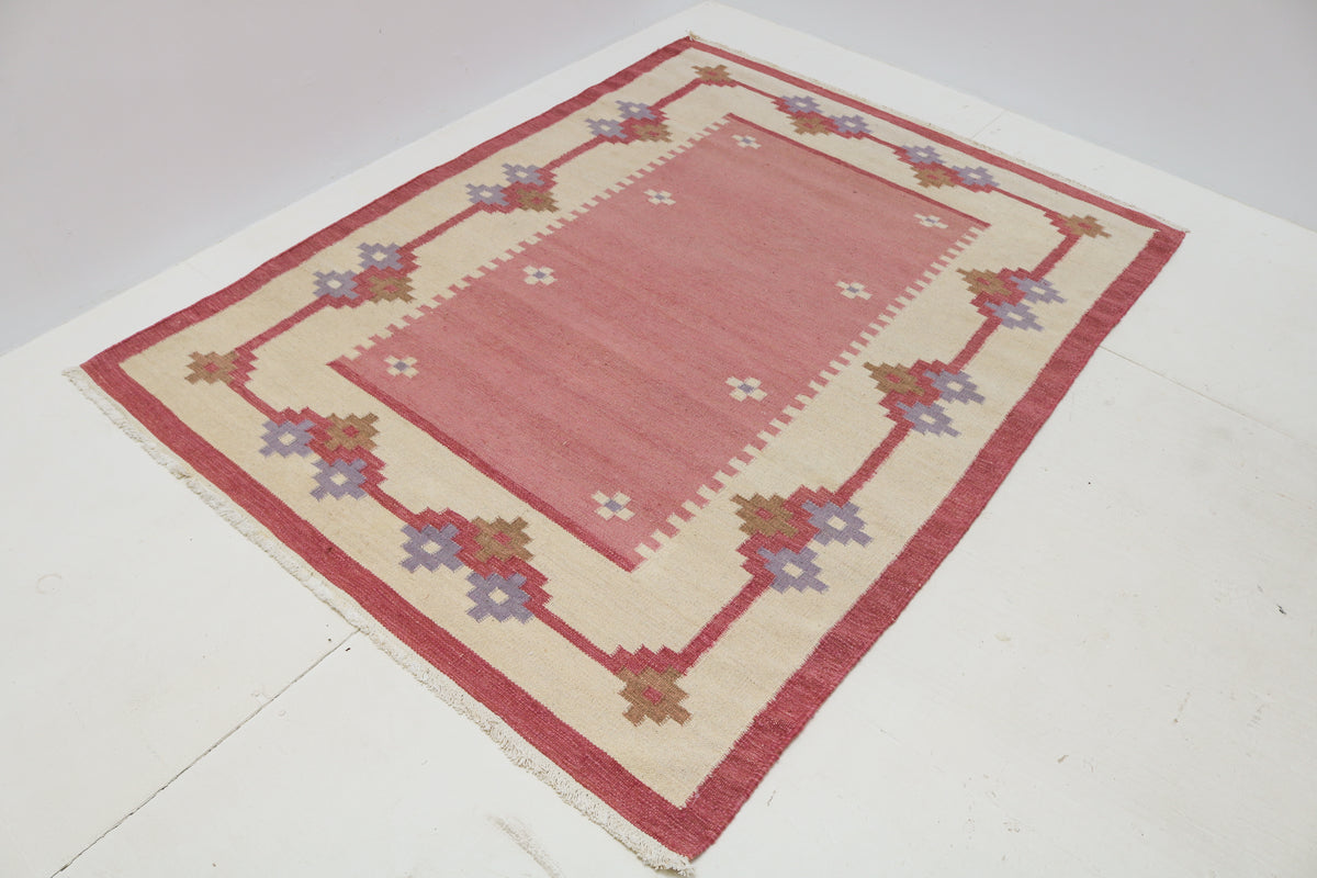 Vintage Swedish Kilim rug showcasing a dusty pink field with geometric floral border