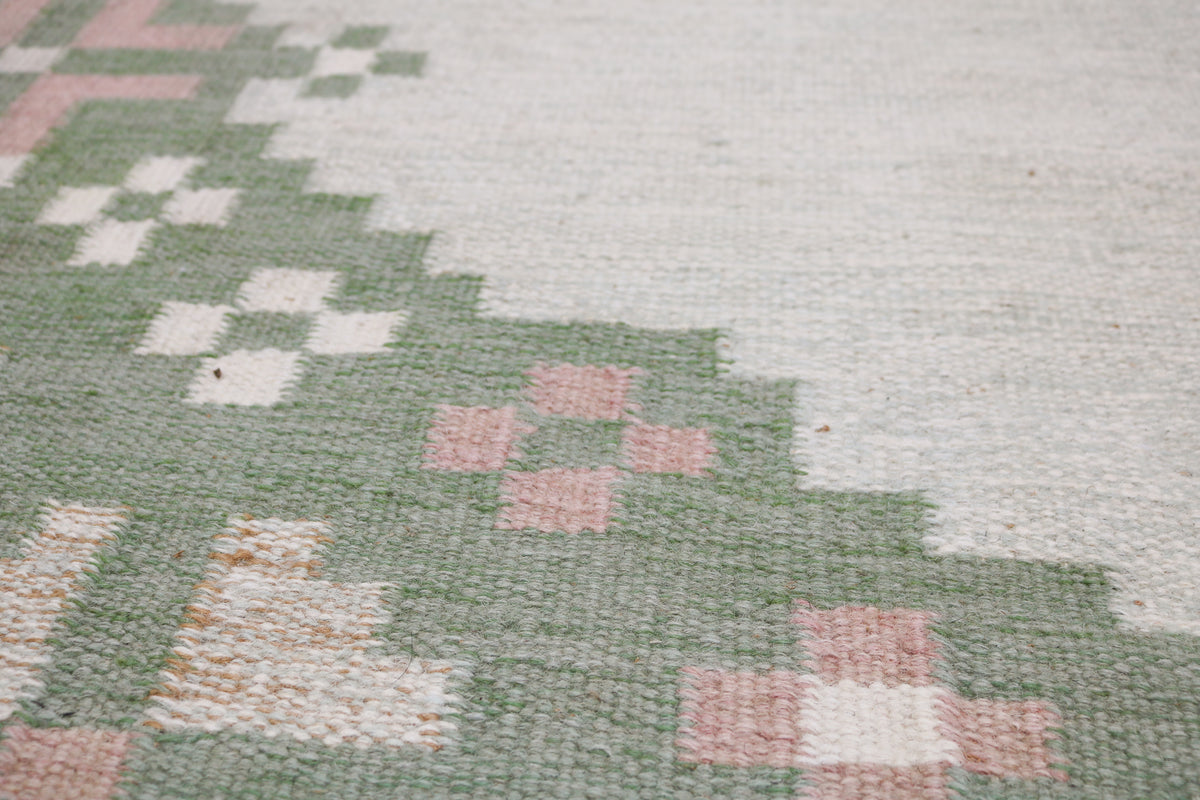 Vintage Swedish Kilim rug showcasing a pale grey centre with repeating green and pink motifs