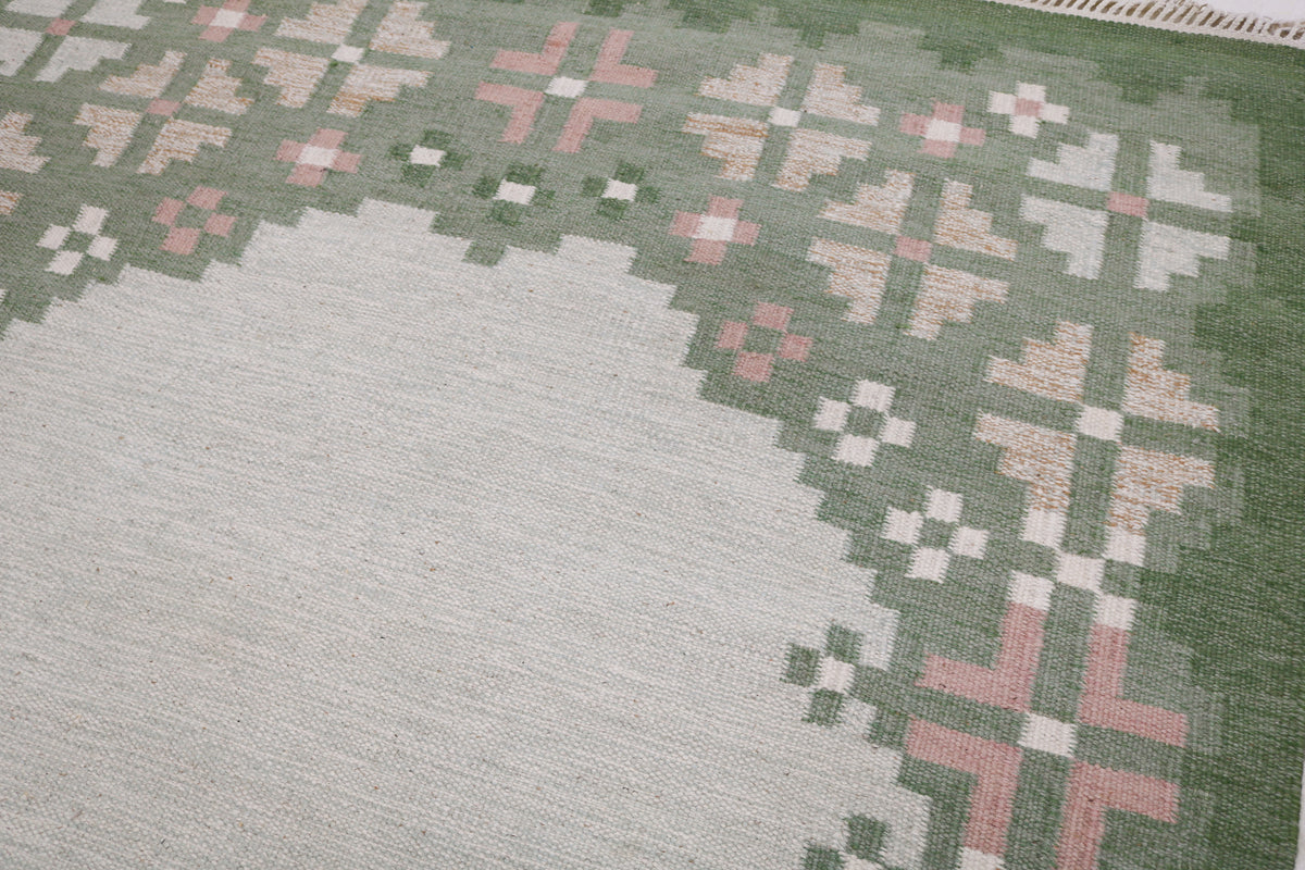Detailed view of Swedish Kilim rug with spacious pale grey field and patterned border