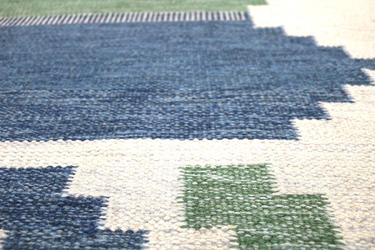 Close-up of vintage Swedish Kilim rug showing blue geometric bands and subtle green accents
