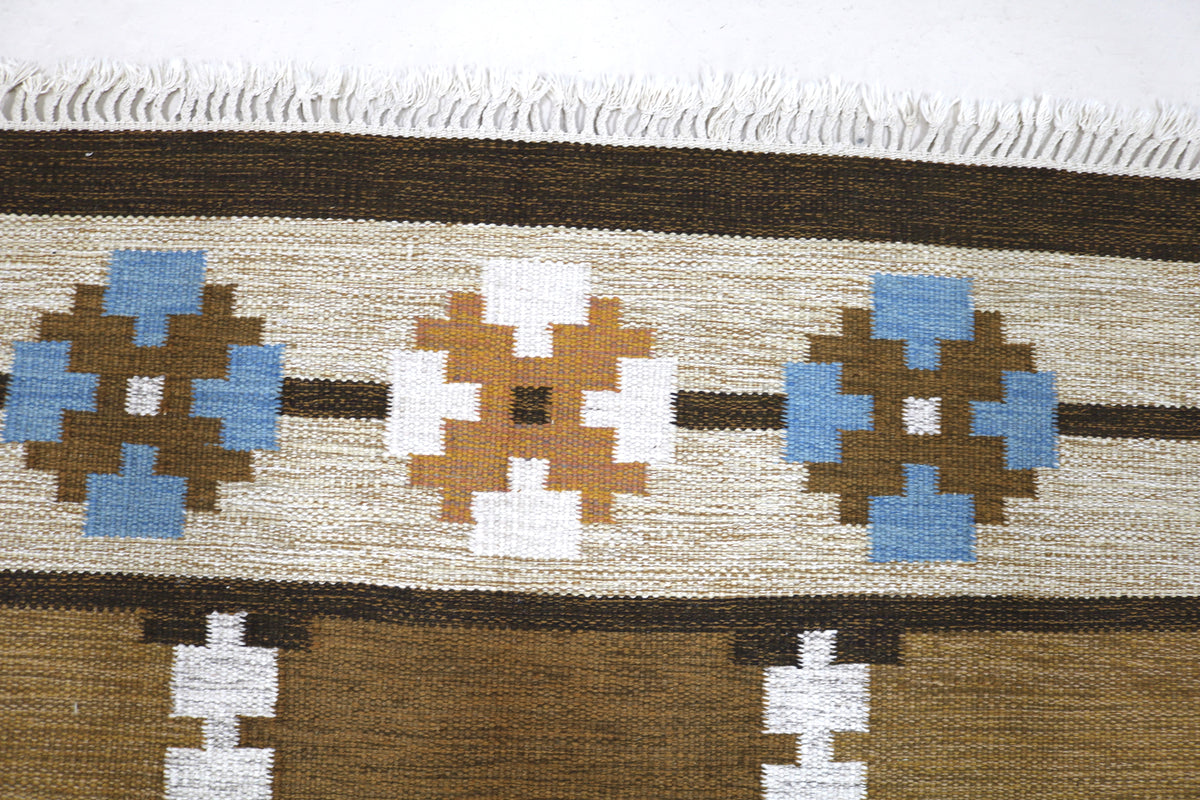 Close-up of vintage Kilim rug showing colourful geometric motifs across brown horizontal bands