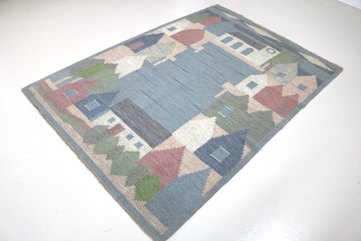 Angled view of vintage Swedish Kilim rug with colourful village landscape composition
