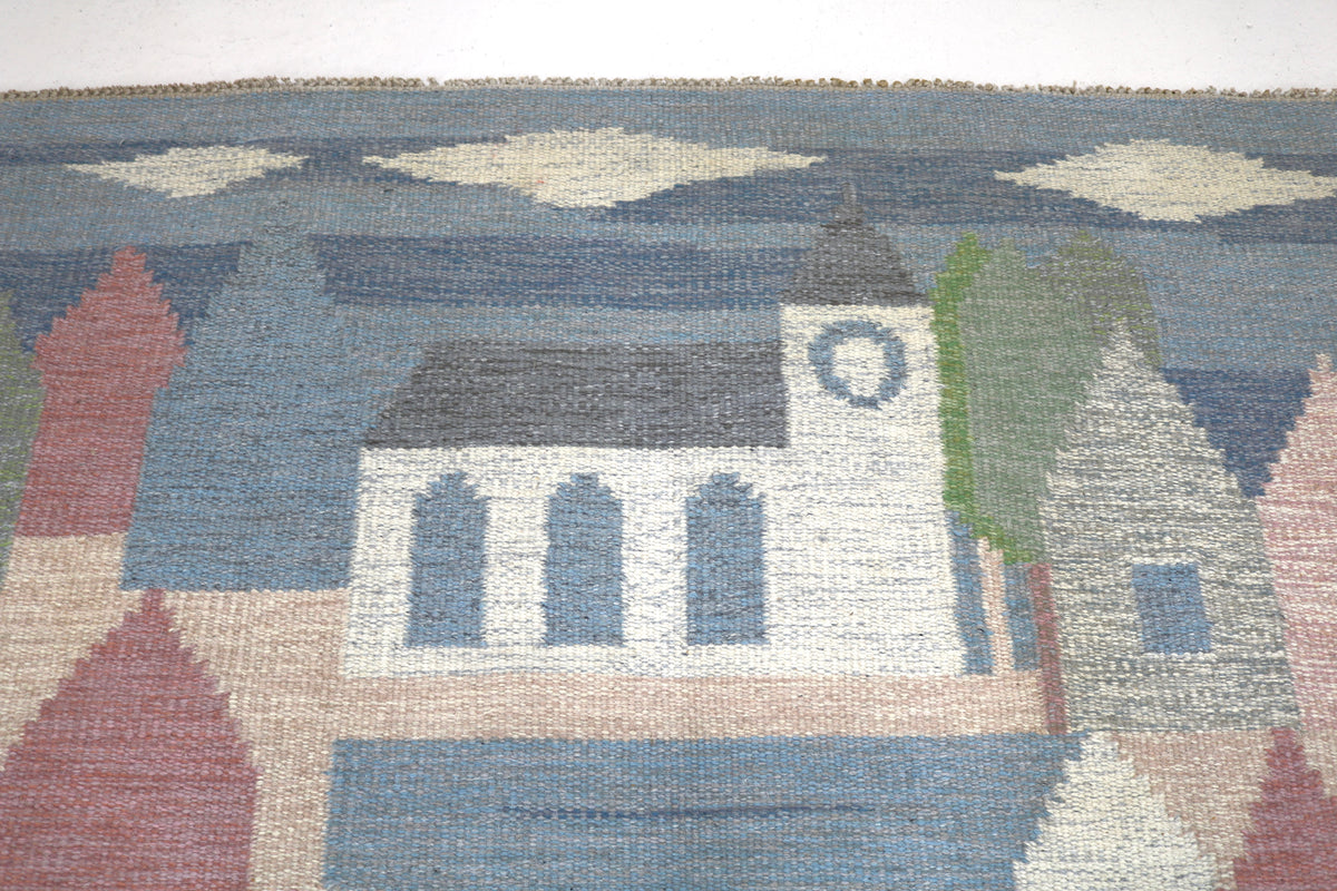 Detailed Swedish Kilim rug featuring colourful houses and rolling hills in geometric forms