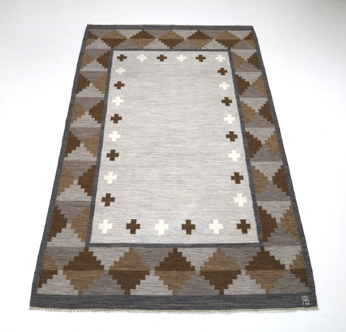 Angled view of Swedish Kilim rug featuring geometric motifs in ivory, taupe and warm brown
