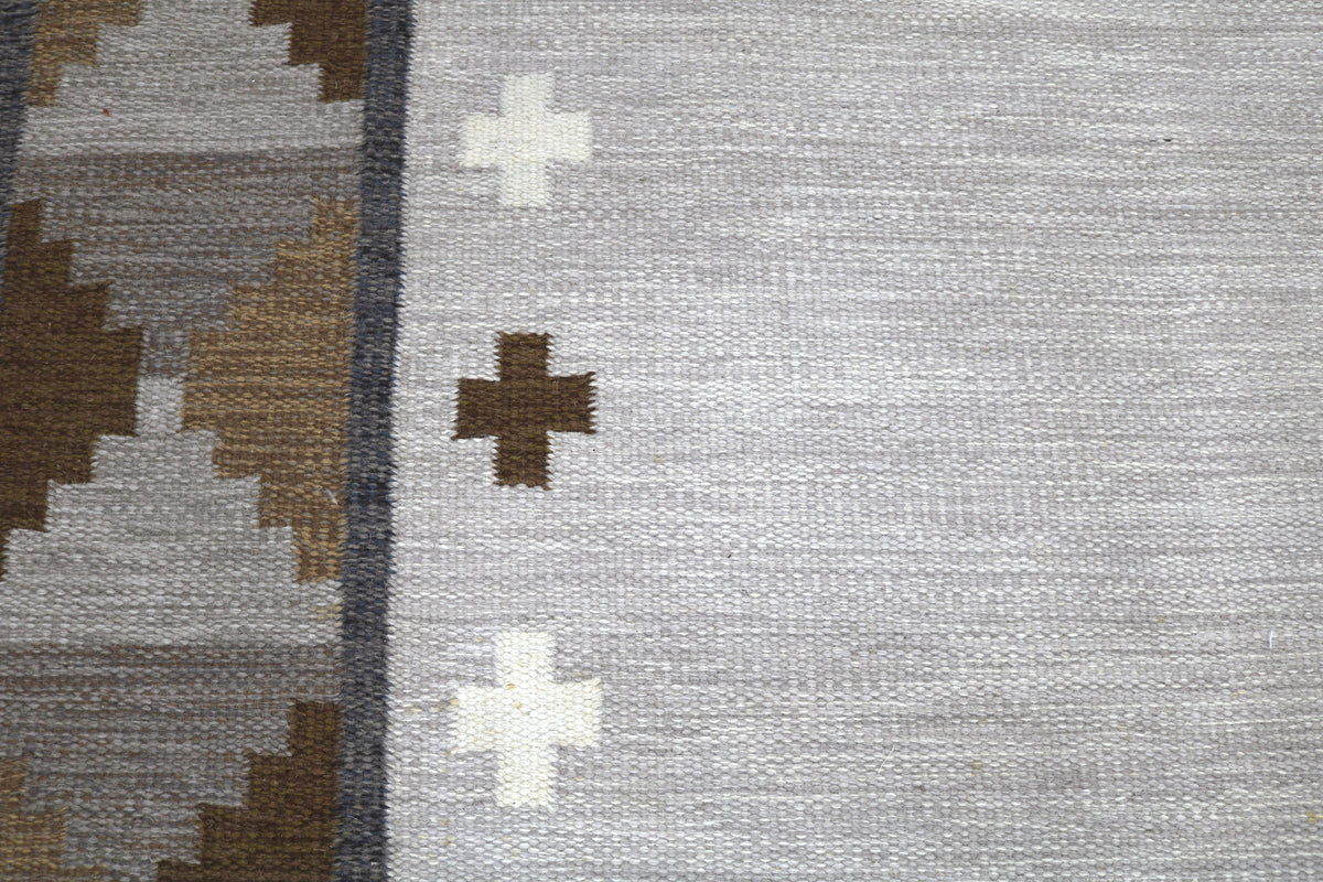 Detailed Swedish Kilim rug surface featuring minimalist cross motifs and geometric borders
