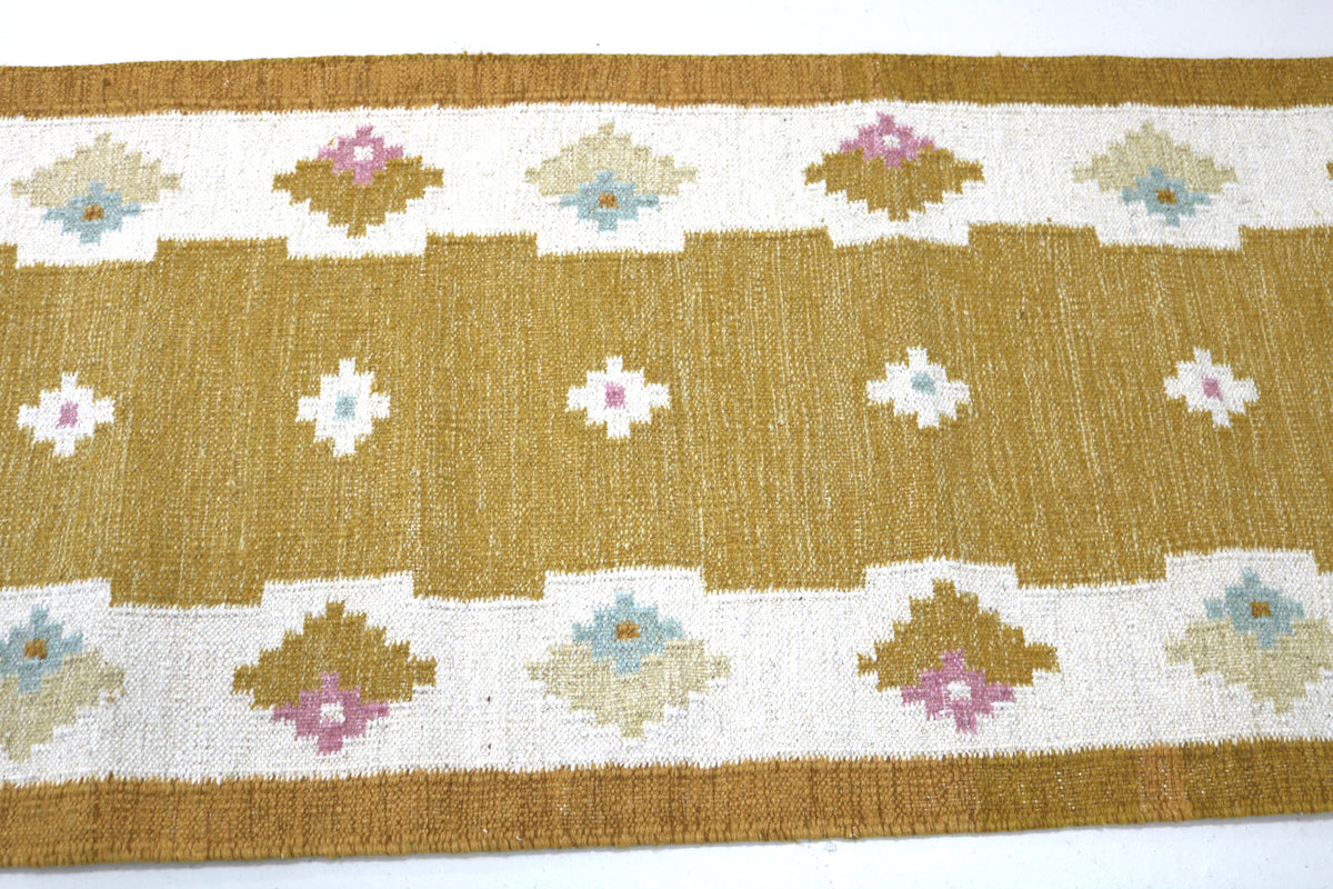 Close-up of vintage runner featuring repeating floral motifs in muted Scandinavian colours