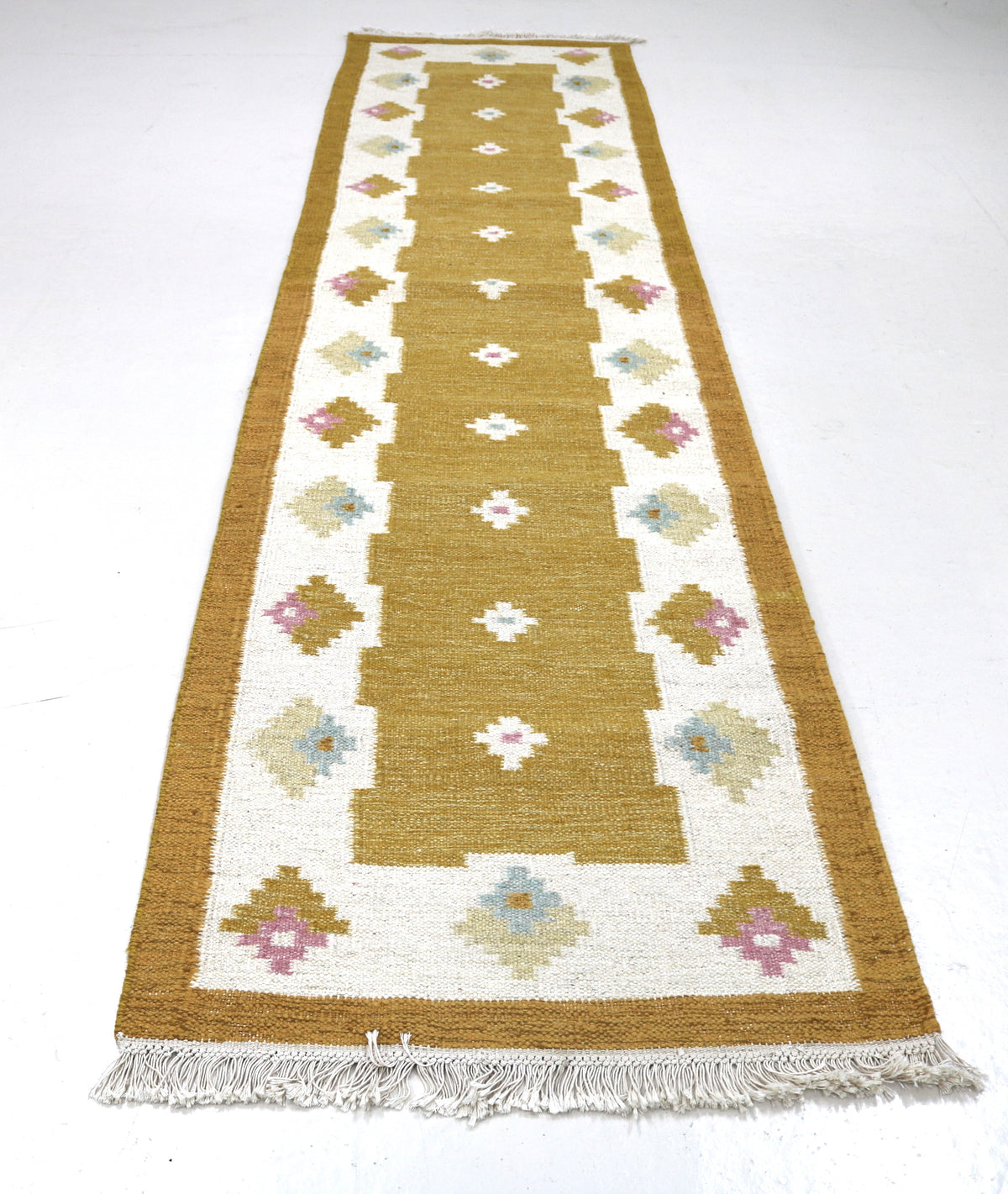 Full-length Swedish Kilim runner featuring repeating geometric floral motifs in warm ochre