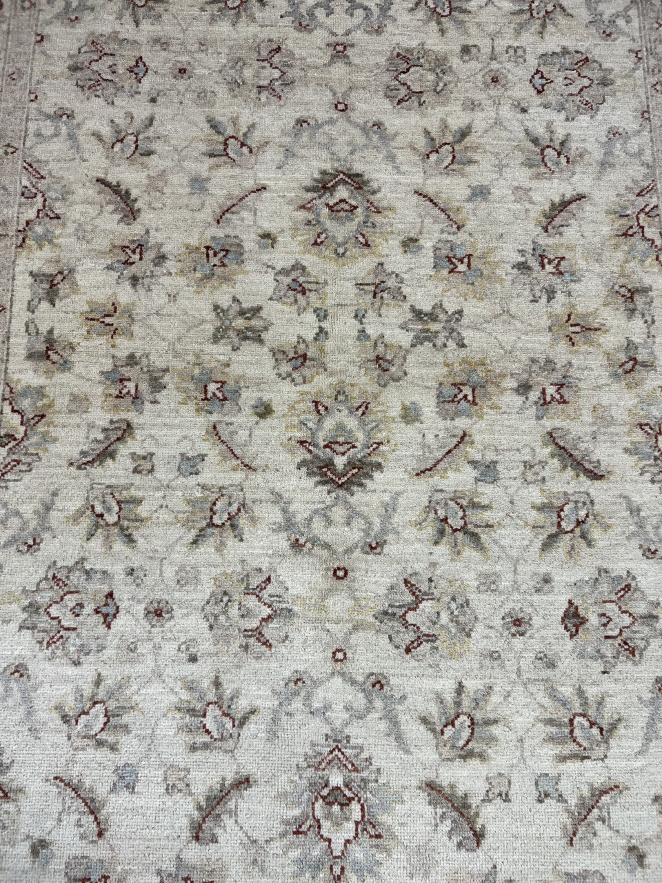 Close-up of Afghan Ziegler rug with repeating floral motifs and muted earthy accents