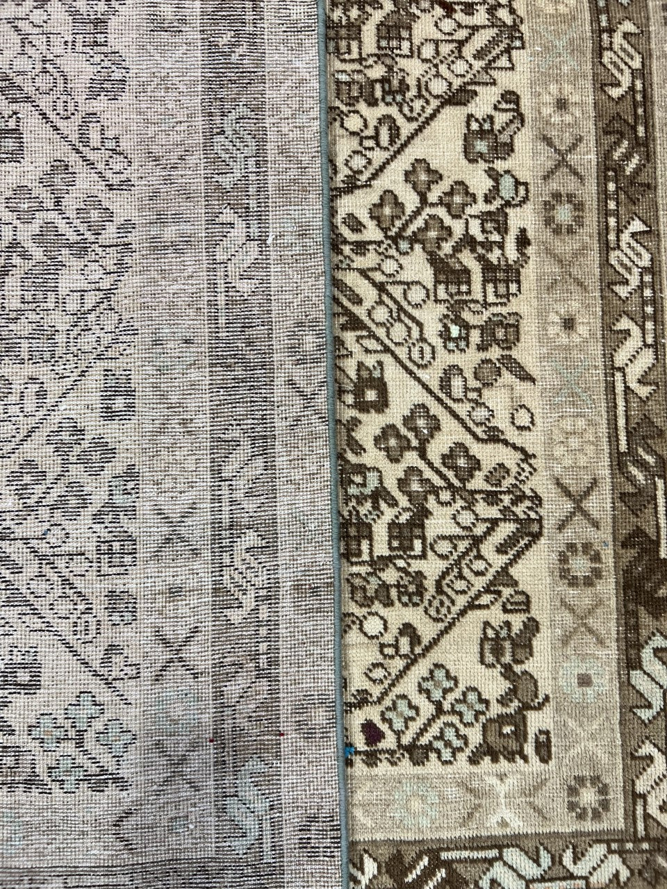 Side view of folded rug revealing contrasting geometric borders and textured reverse