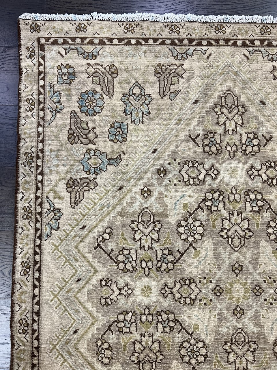 Close-up of Malayer rug featuring floral motifs in muted blue, beige and brown
