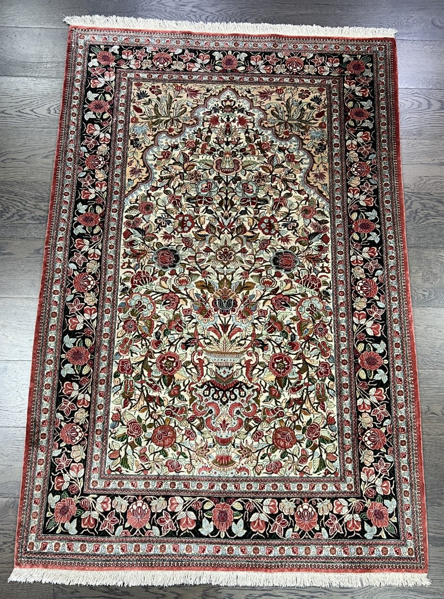 Full Qom silk rug showing elegant prayer niche and densely detailed floral field
