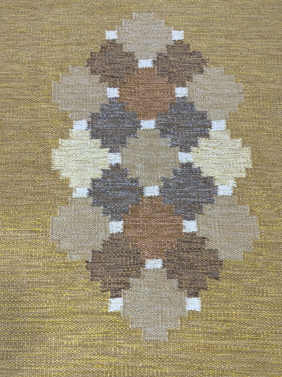 Close-up showing clustered diamond shapes across the warm ochre field