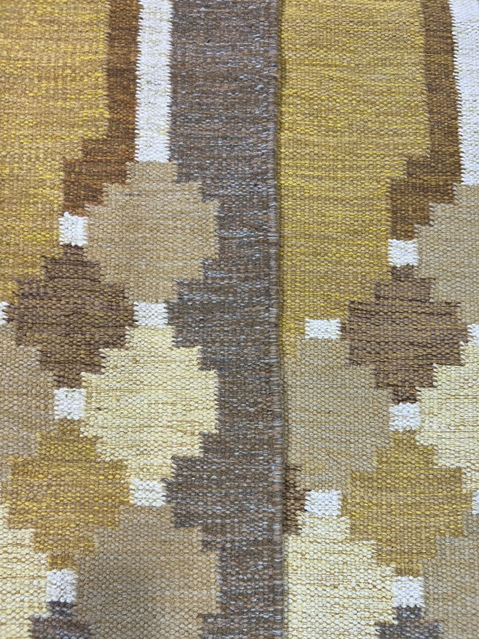 Close view of repeating diamond motifs against a muted ochre background